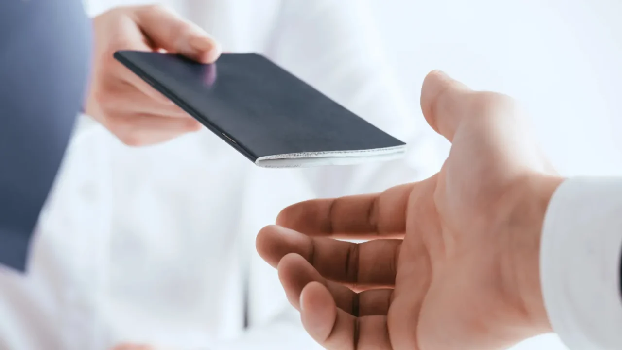 cropped view of travel agent giving passport to tourist isolated