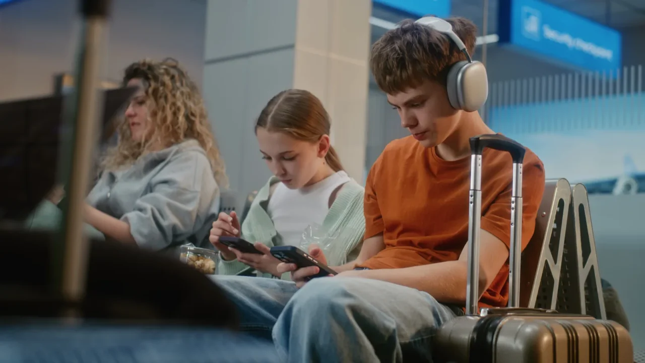 crowded international airport terminal boy and girl teenage siblings using