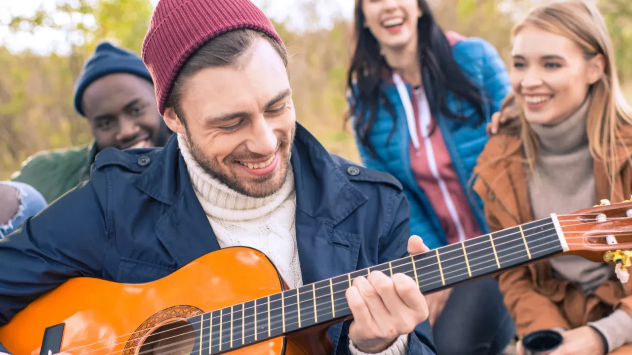 friends enjoying guitar in autumn park