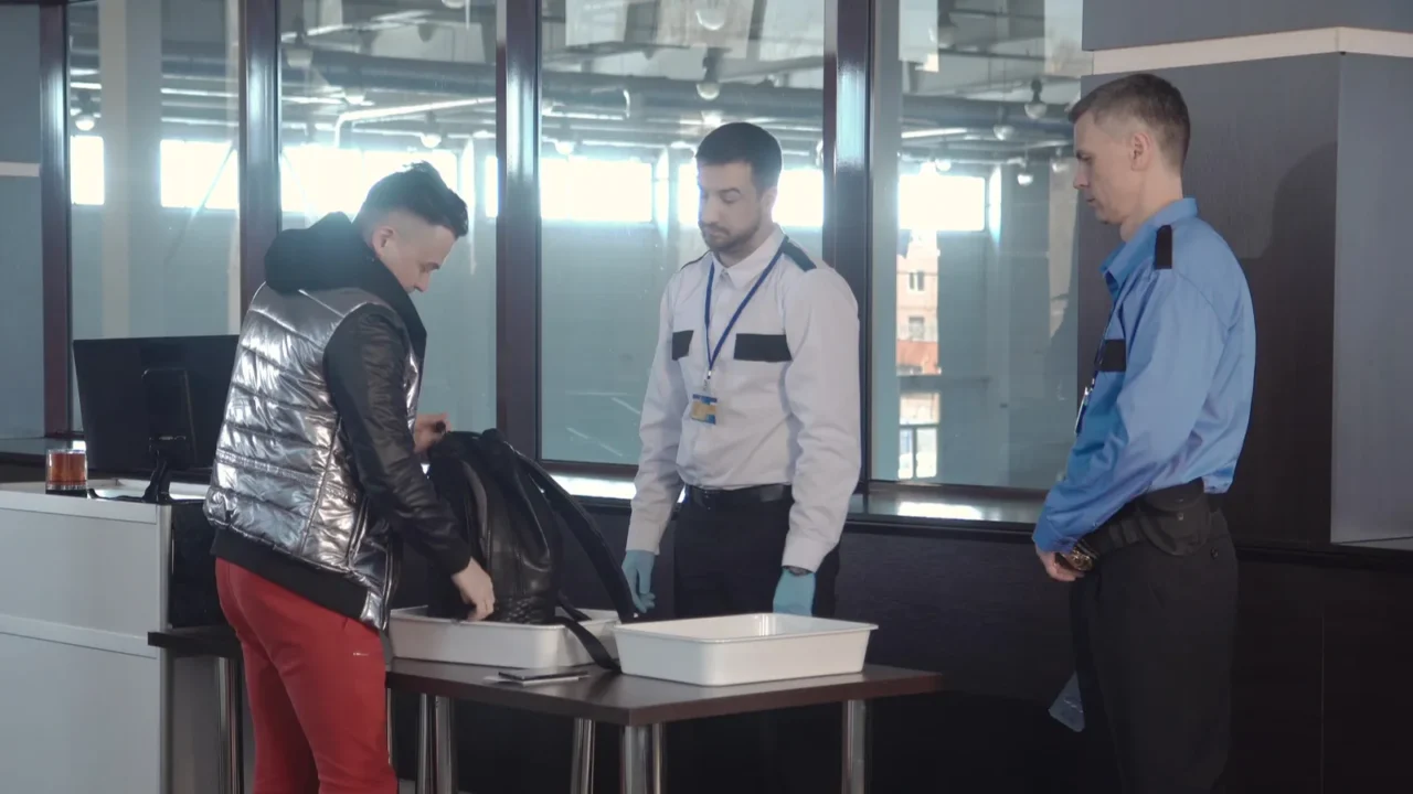 guard checking passenger bag in airport