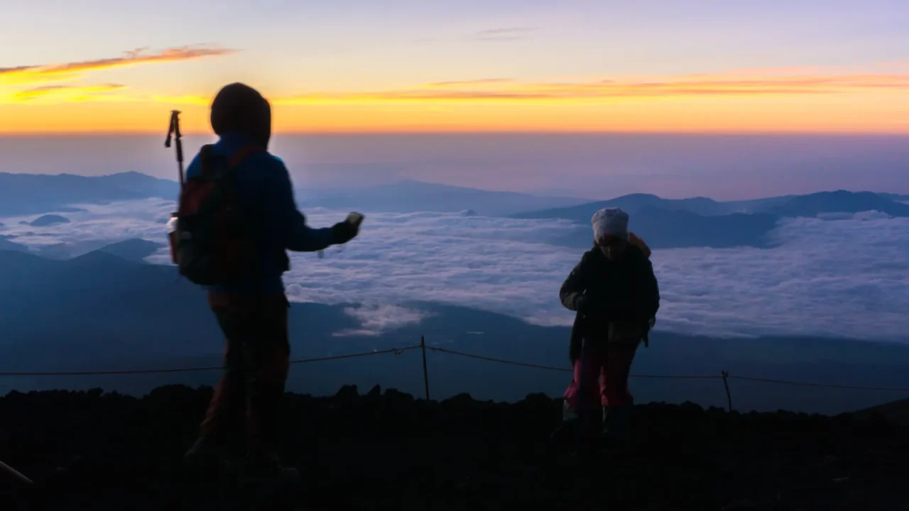 hikers gather during sunrise on the mt fuji summit