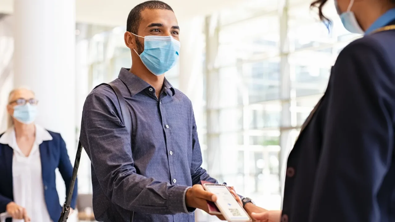 indian passenger wearing surgical mask showing eticket to flight attendant