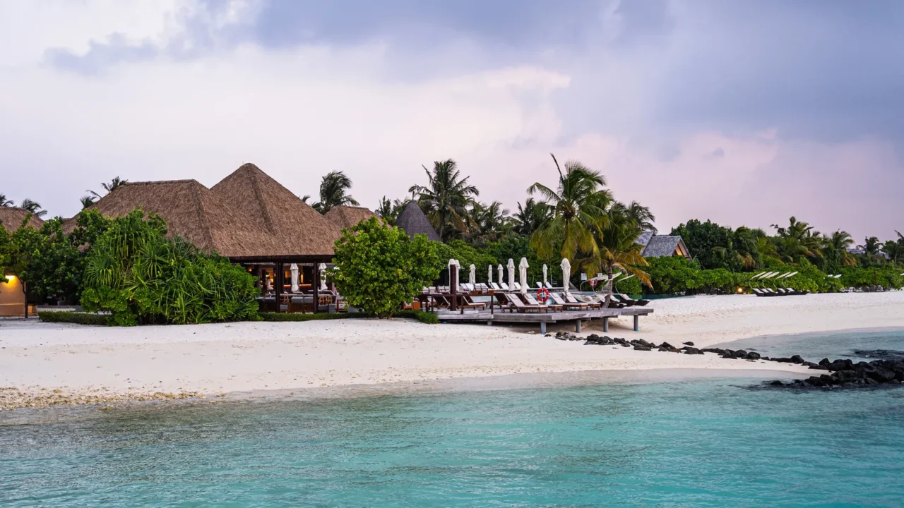 luxury beachfront resort with thatchedroof villas surrounded by tropical greenery