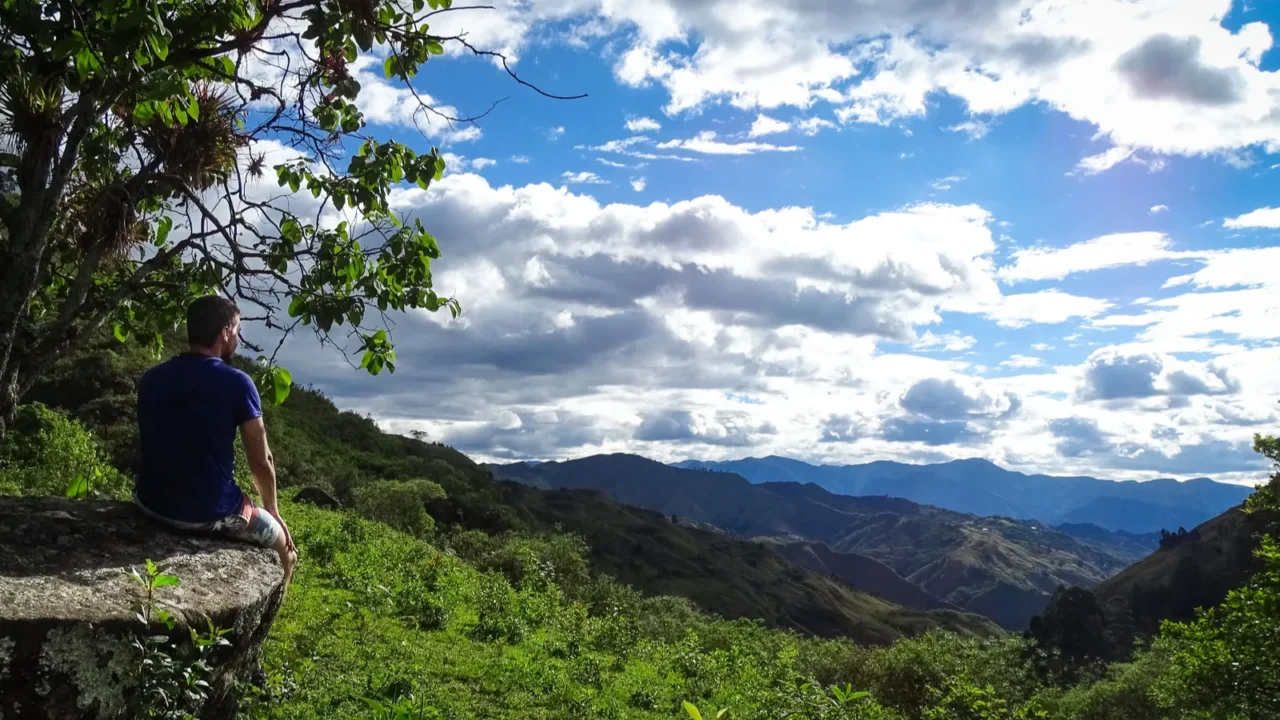 man sitting on a rock looking at a ecuadorian beautiful