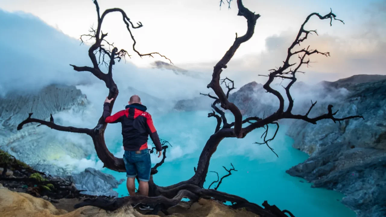 man traveler on edge of crater ijen volcano with colorful