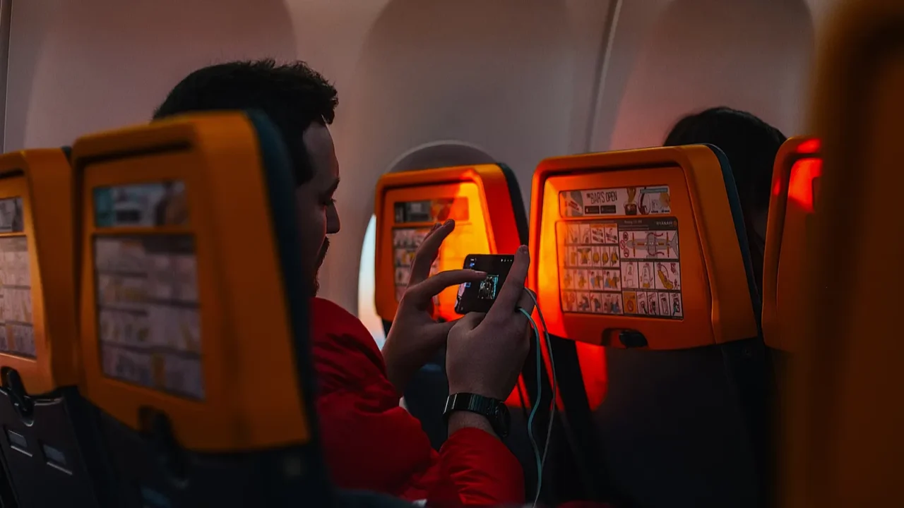 man using smartphone while sitting in airplane