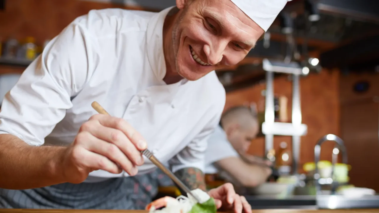 portrait of professional chef plating asian seafood dish in restaurant