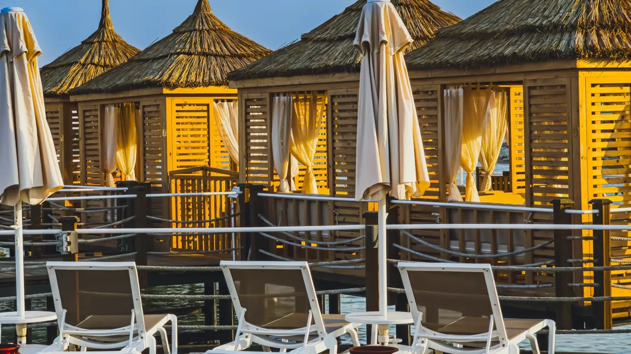 row of luxury beach cabanas with curtains and sun loungers