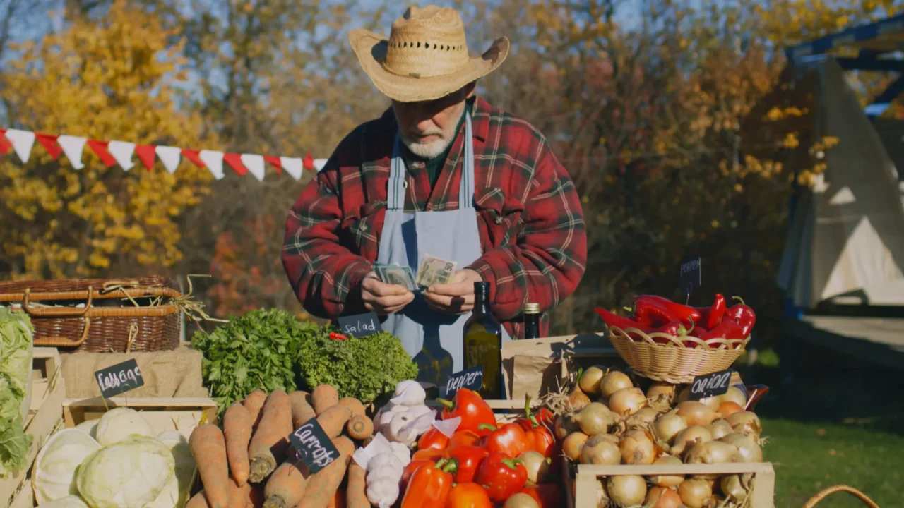 senior farmer seller stands at the stall with fruits and