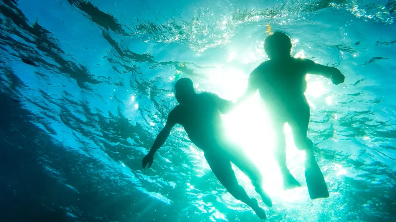 silhouette of senior couple swimming together in tropical sea