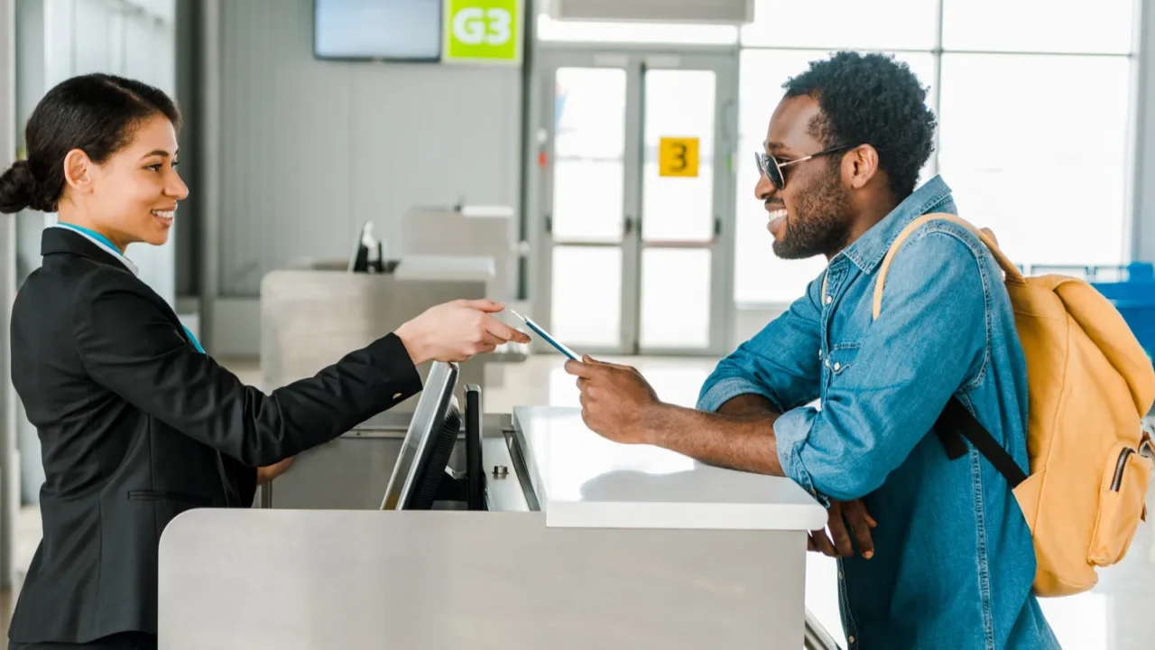 smiling african american airport worker taking passport and air ticket
