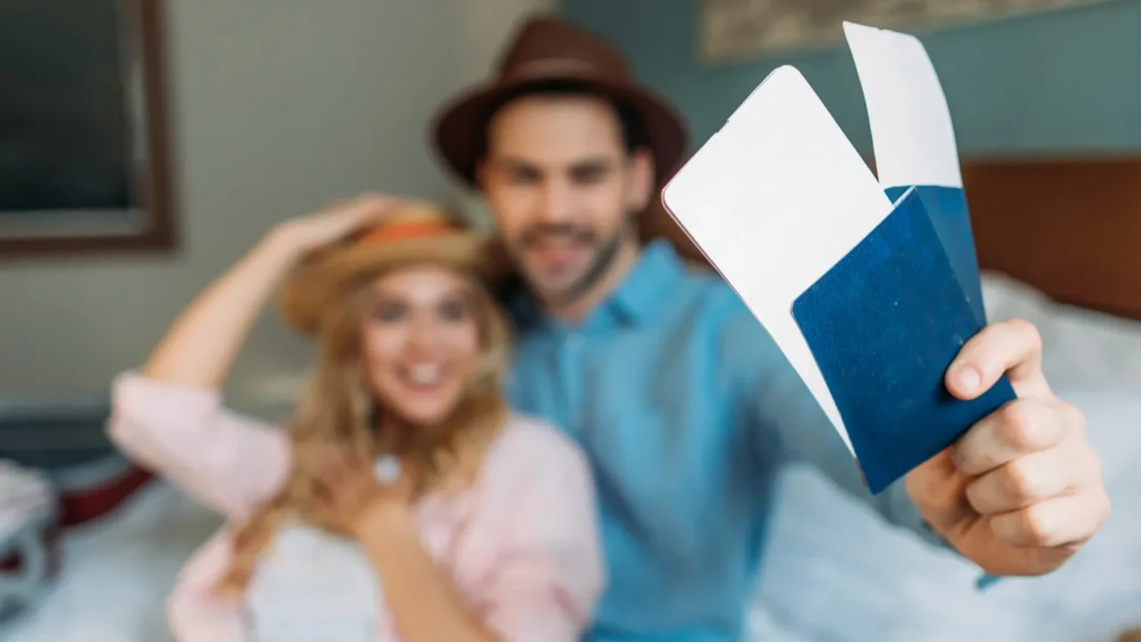 smiling couple in hotel room with passports with tickets on