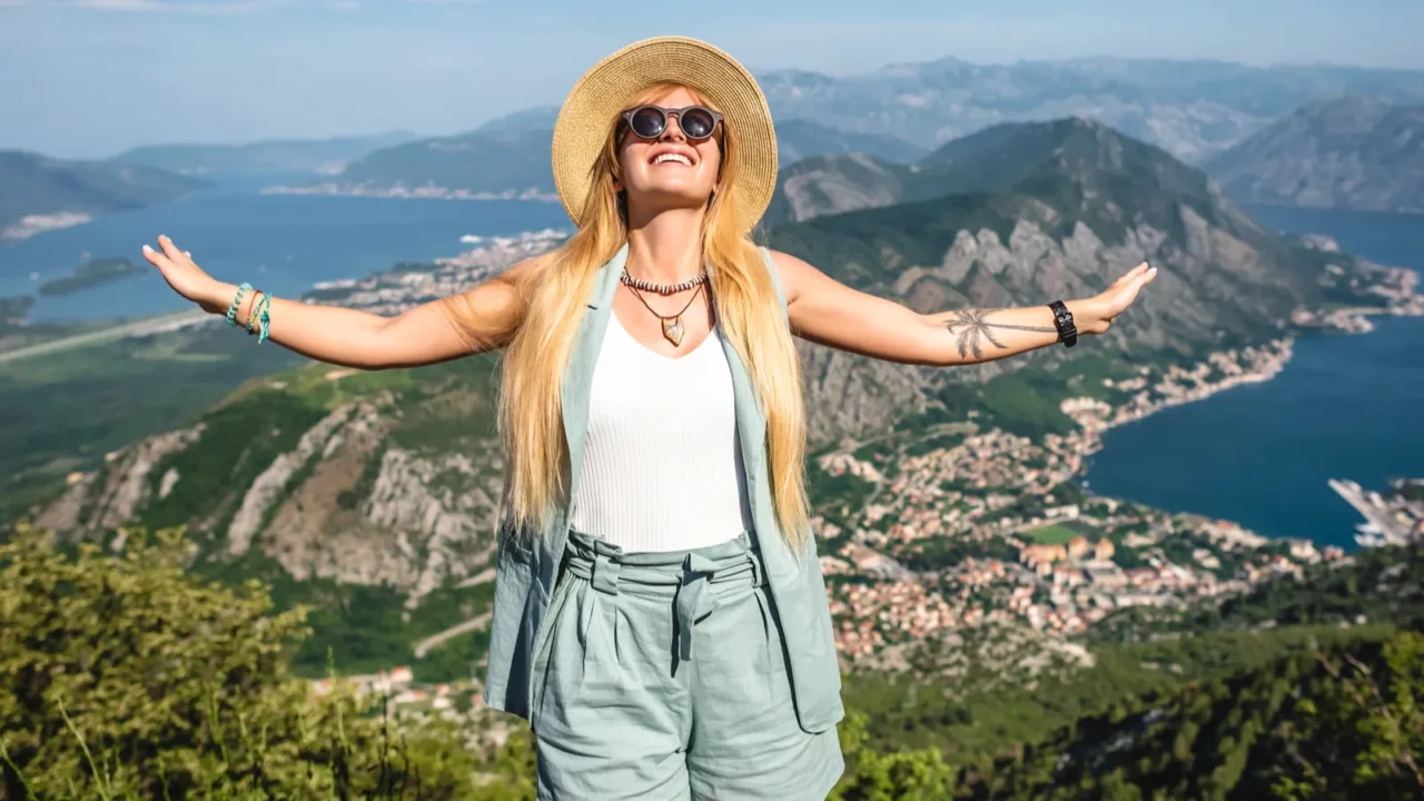 smiling woman standing with open arms kotor bay and kotor
