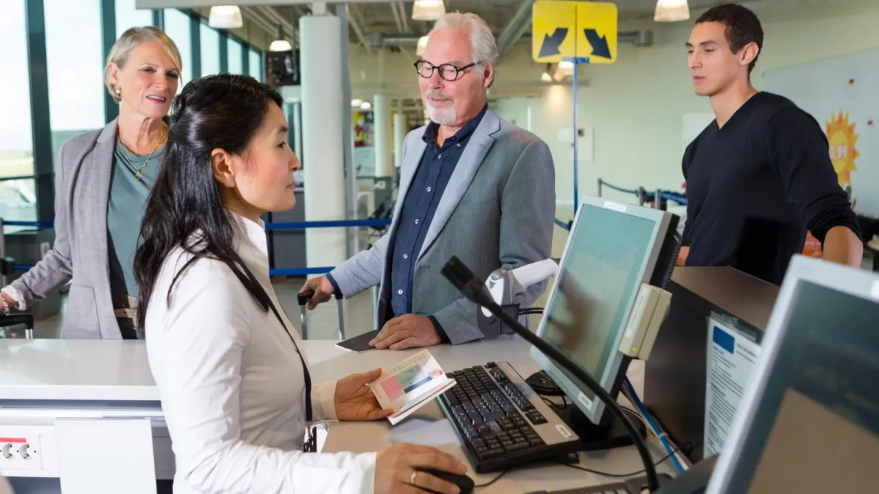 staff checking passport on computer while passengers waiting in