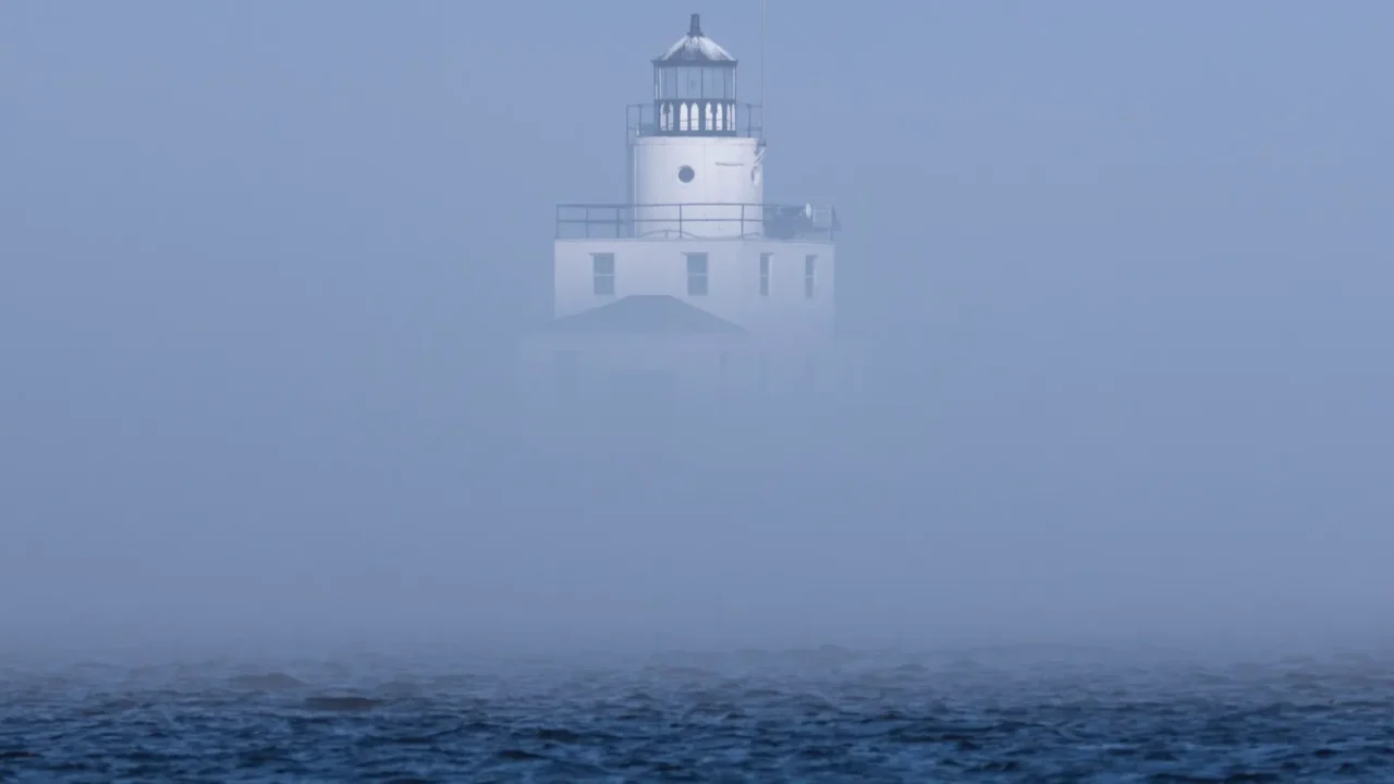 the thick fog partially obscures the lighthouse on lake michigan
