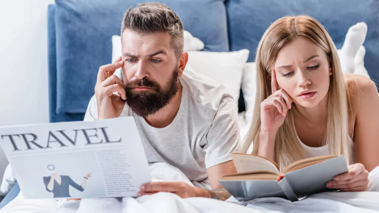 thoughtful man holding travel newspaper while pretty girl reading book