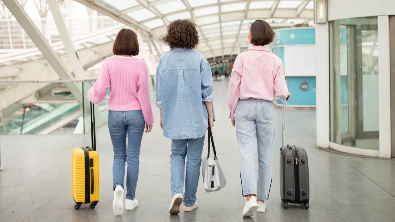 three young women stroll through a modern airport terminal each