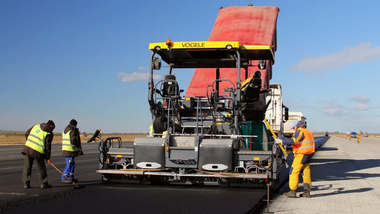 tracked paver laying fresh asphalt pavement