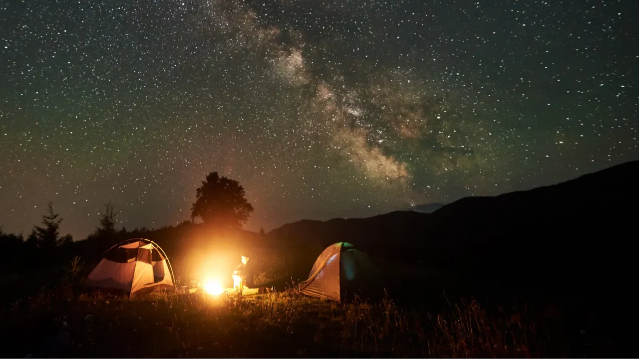 woman camper resting at night camping in mountains under amazing