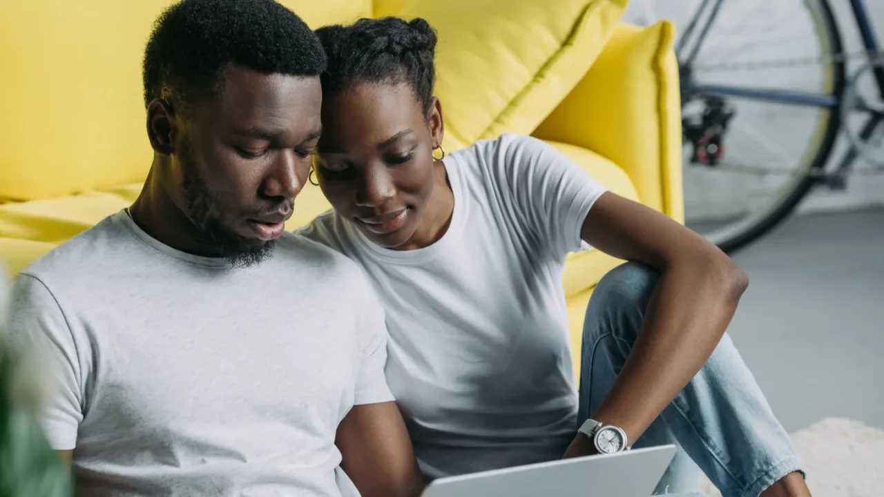 young african american couple in white tshirts using laptop together