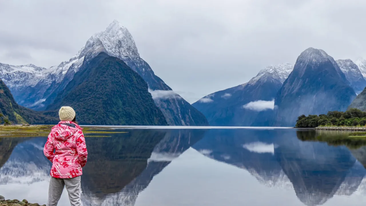 young asian traveler girl from back standing at milford sound