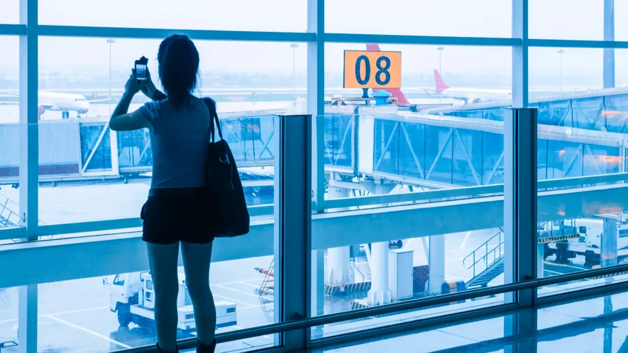 young girl at the airport window and flight arrival