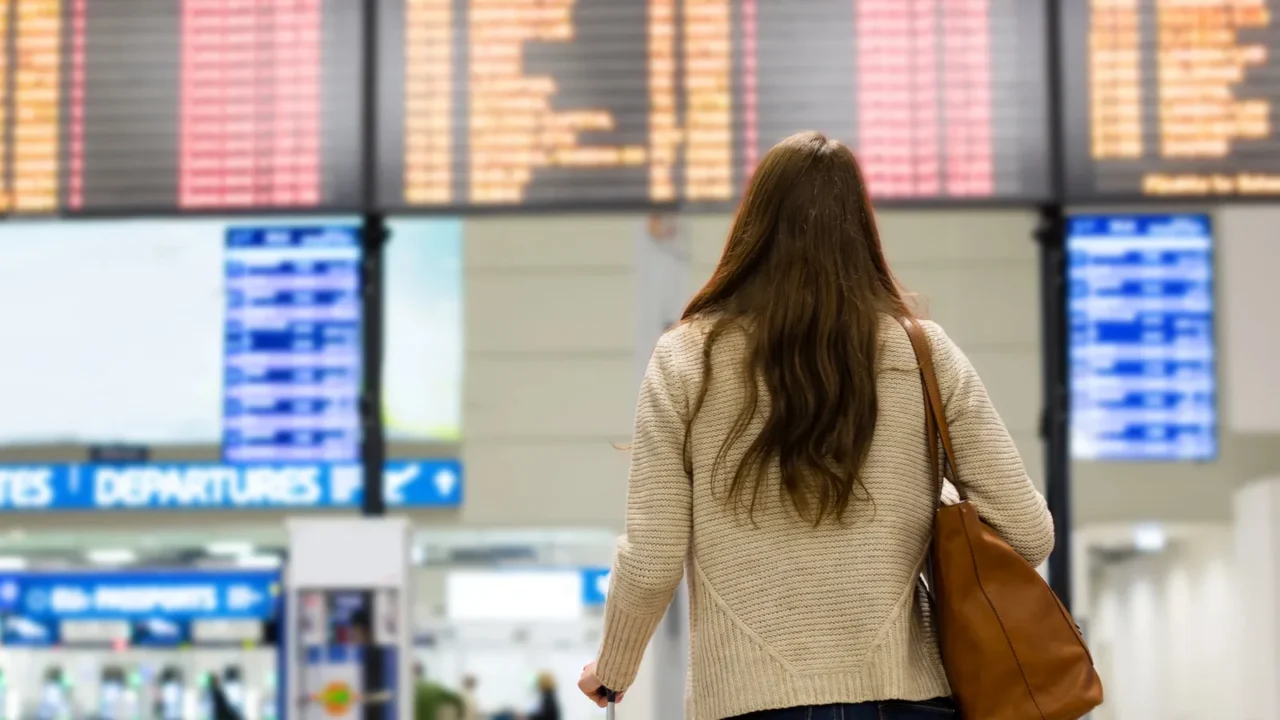 young woman looking at the flight information board on the