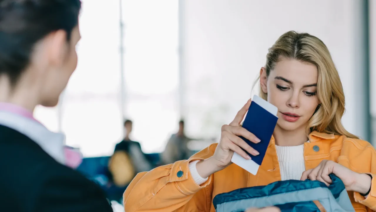 young woman putting passport with boarding pass into bag at