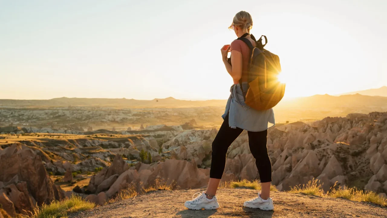 young woman traveler with backpack looking at beautiful view with