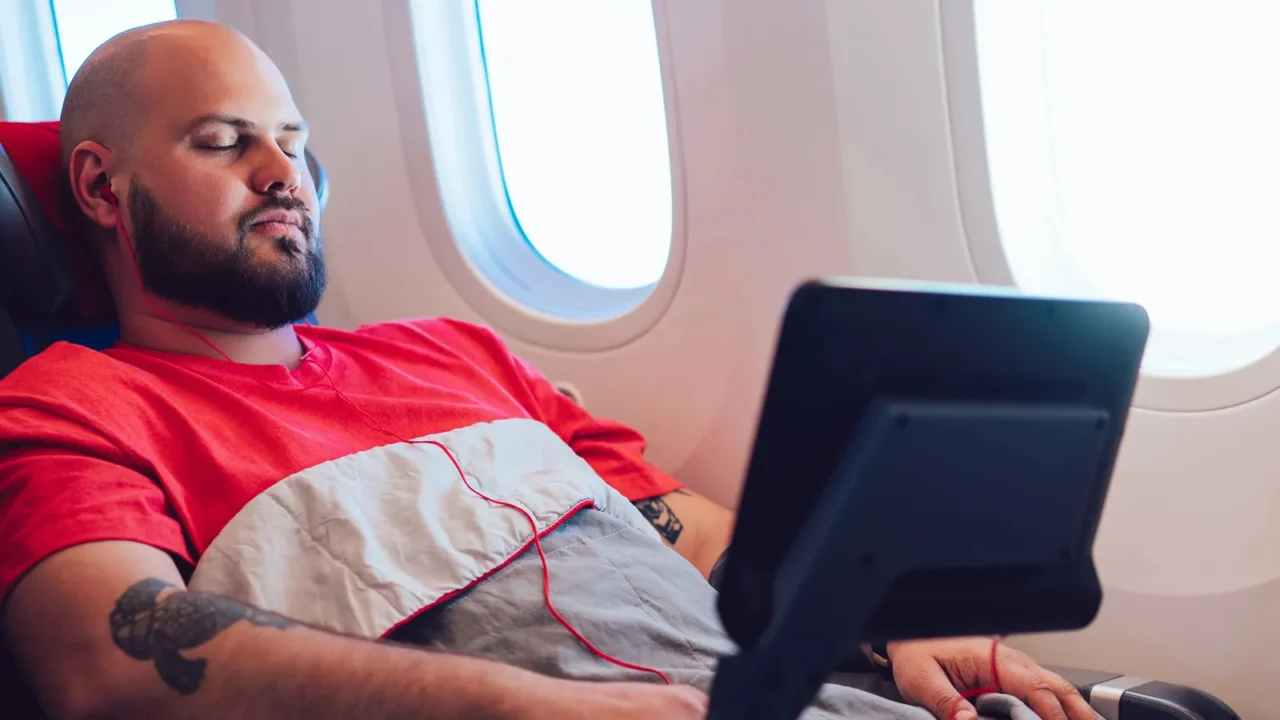 30 years old caucasian man sleeping on wide seat cowered