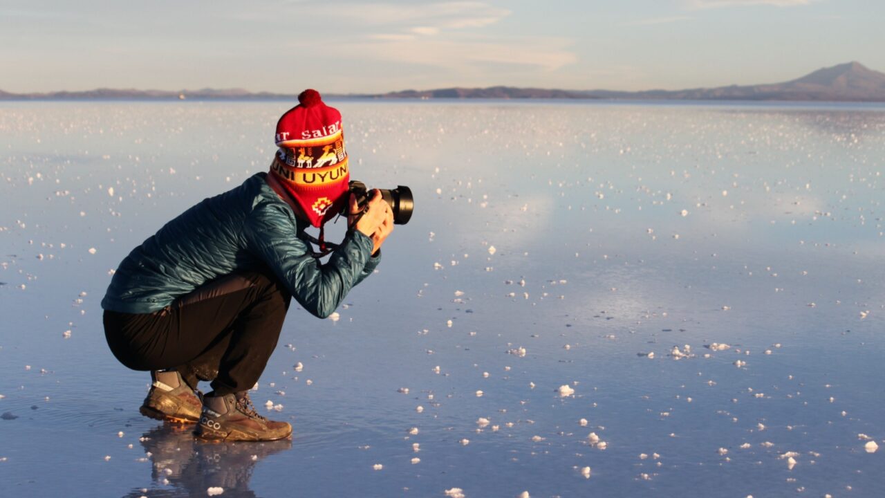 Uyuni, Bolivia - June 02, 2025: Salar de Uyuni salt flat turns into a shallow lake during rainy season and becomes world's largest natural mirror, featuring reflection. Tourist takes digicam photo.