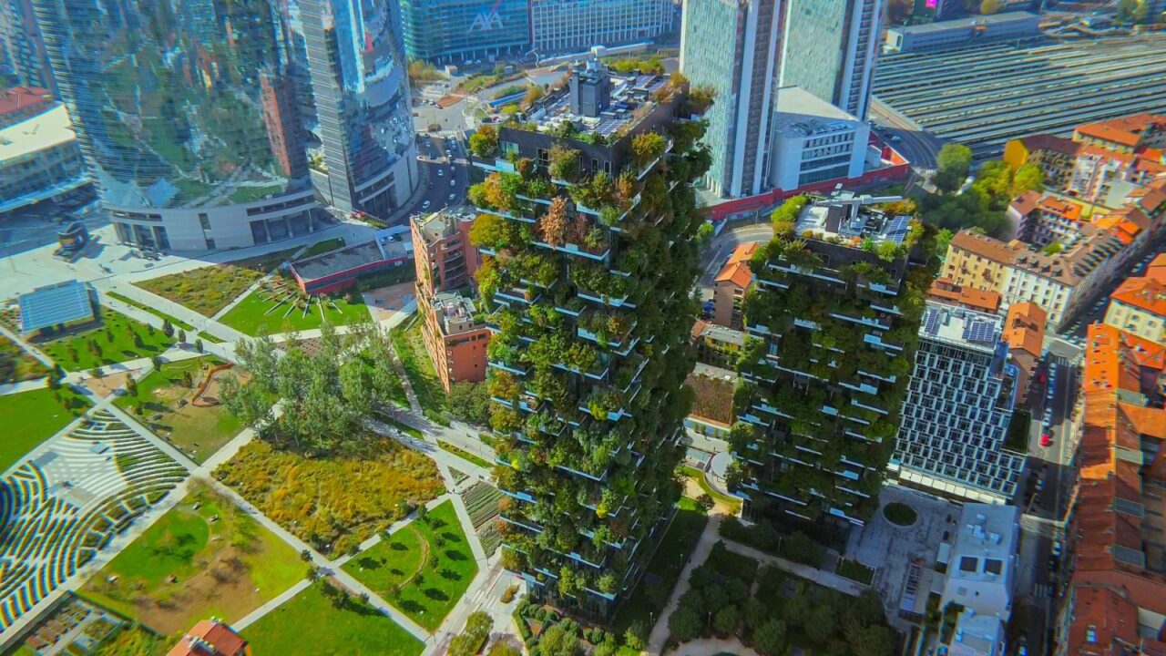 Aerial view of ecological skyscrapers with autumn trees on balconies. Bosco Verticale. Modern architecture, vertical gardens, terraces with plants. green Planet. blue sky. Milan, Italy, 11.2022