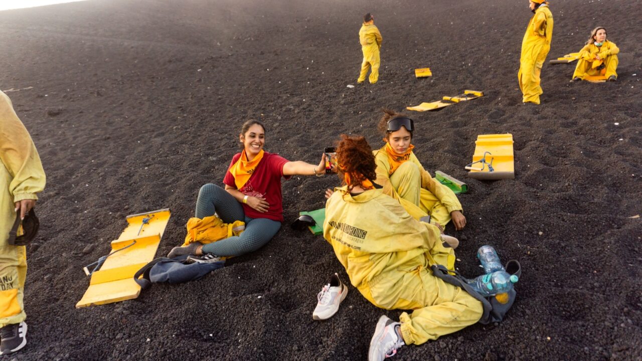 Leon, Nicaragua - April 19, 2025; tourists resting on black volcanic sand after sandboarding down cerro negro volcano slope, experiencing adventurous moment in Leon, Nicaragua landscape