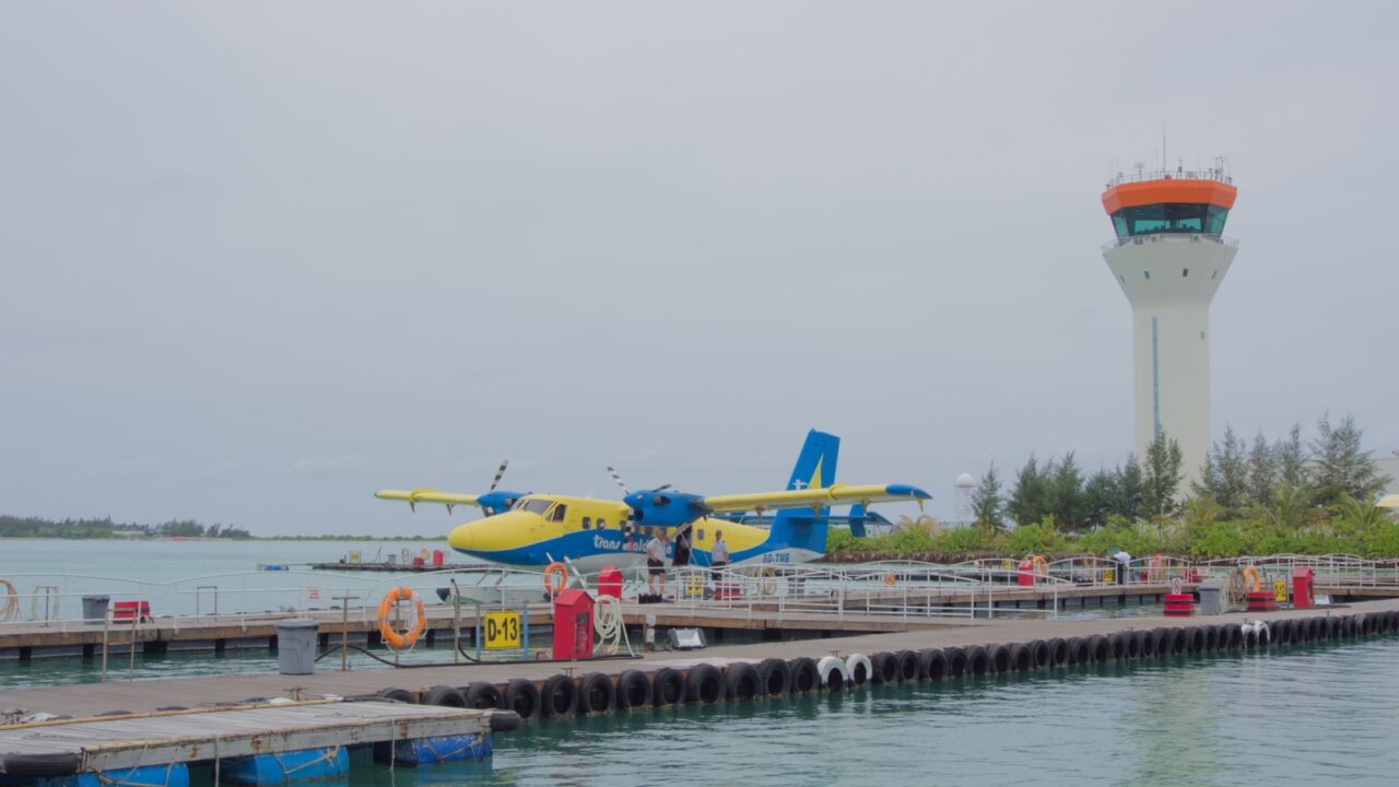 Velana International Airport (MLE), Aug 12, 2014: Trans Maldivian Airways seaplane is docked at the terminal pier with the white and orange Air Traffic Control (ATC).