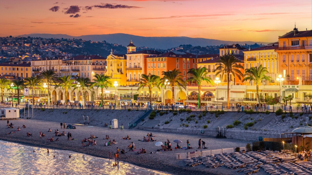 NICE, FRANCE - AUGUST 29, 2019: people walking and swimming at sunset, "Promenade des Anglais", Walkway of the English, pedestrian street along the beach, French Riviera of Mediterranean Sea