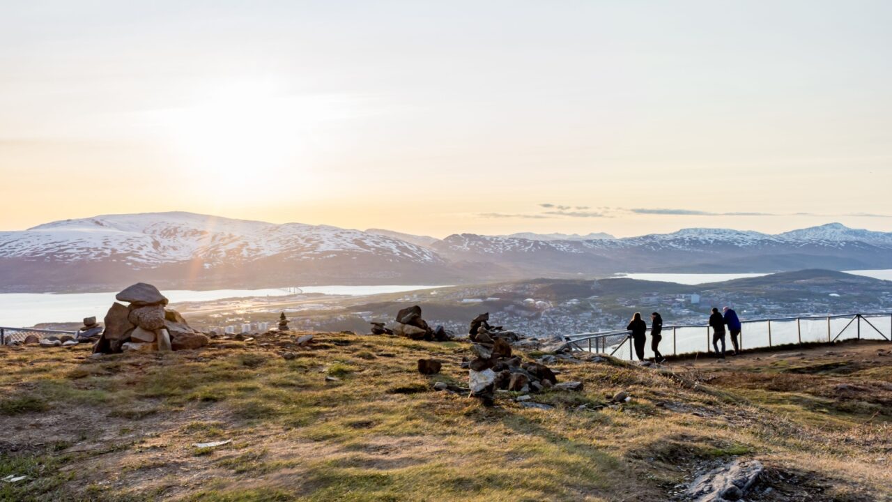 Tromso, Norway - June 03, 2019: People viewing Tromso under the midnight sun from high up the mountainside