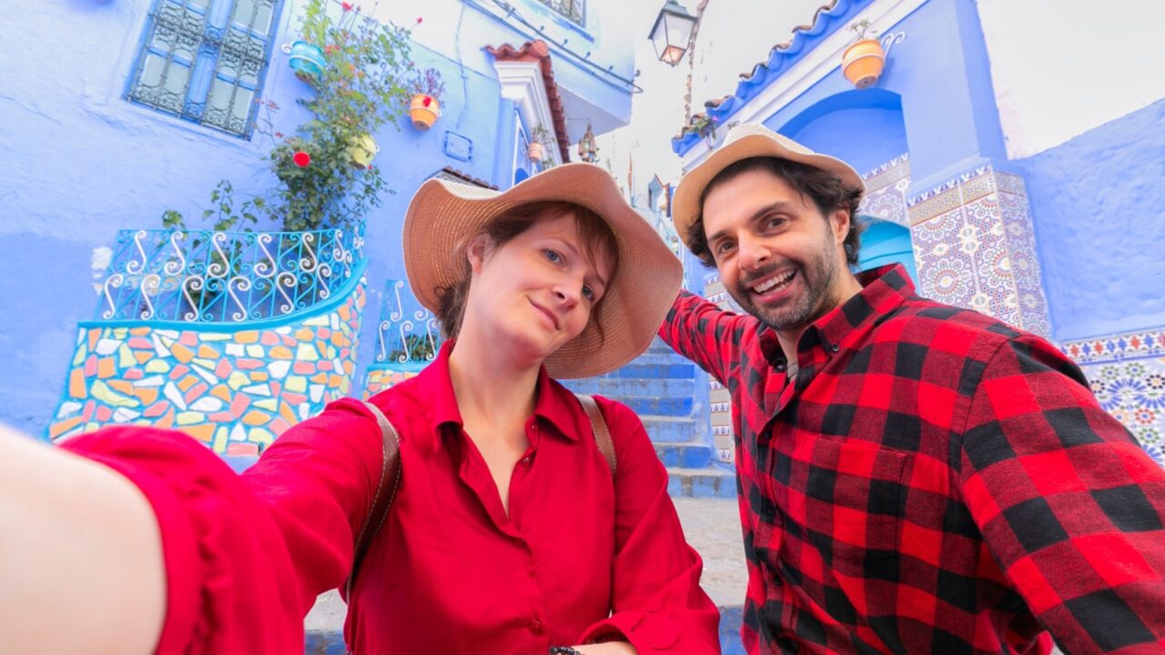 Happy young couple tourist taking selfie on a street in Medina of the blue town of Chefchaouen, Morocco