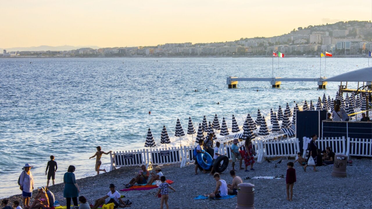 NICE, FRANCE - August 10, 2016: People enjoy a beautiful summer sunset in the Opera Plage, the oldest beach of the French city of Nice.