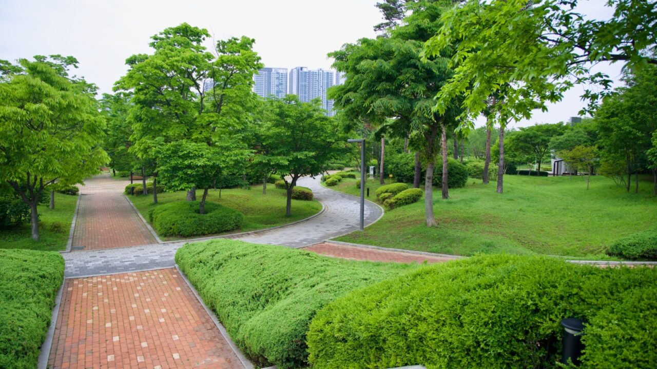 Incheon, South Korea - May 19th 2025: Curving brick and stone walkways wind through vibrant spring foliage in the Sicheon Rest Area park, a peaceful green space near the Ara Waterway with high-rise ap