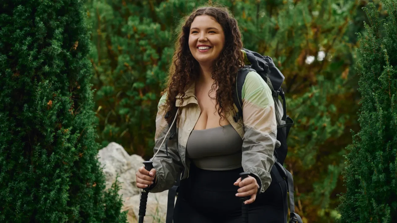 a cheerful plus size woman walks through a lush forest