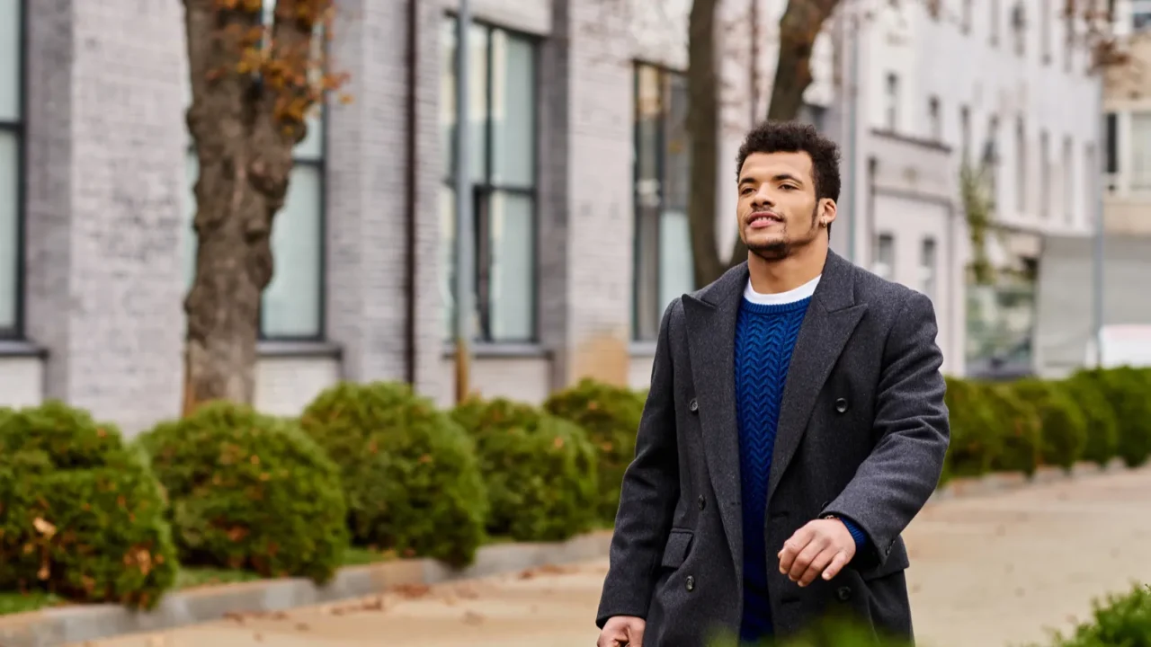 a dapper man walks confidently down the tree lined street