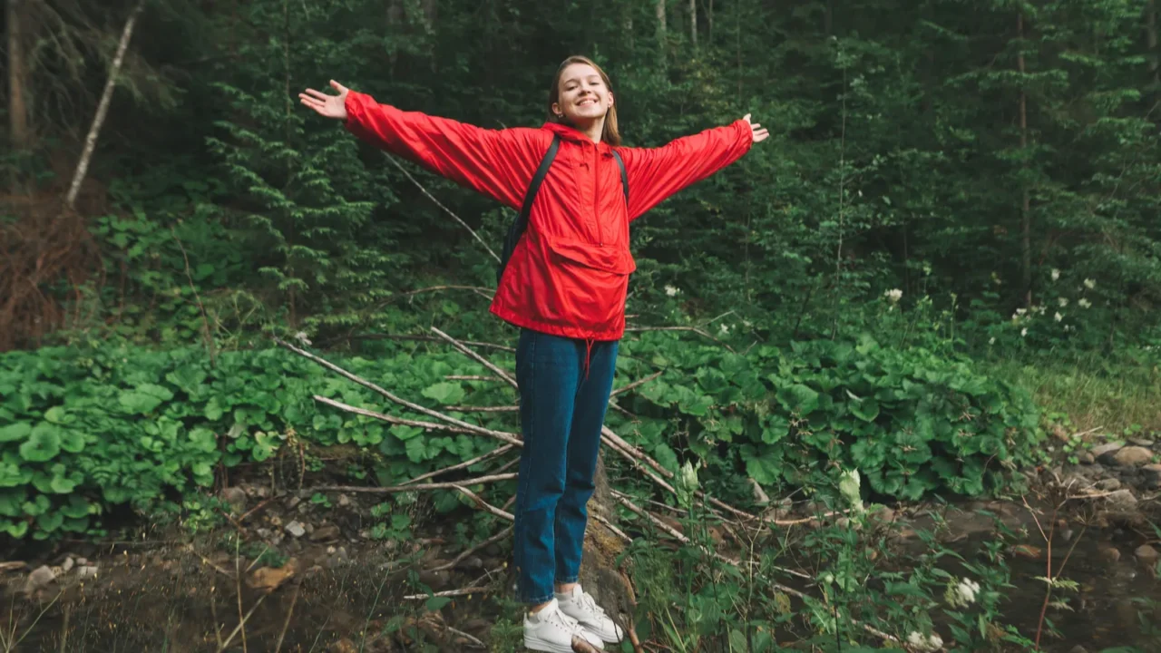 a happy girl in a red raincoat stands on a