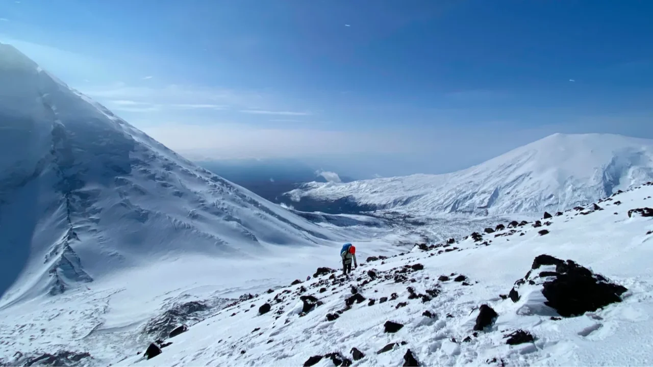 a tourist climbs the klyuchevskaya sopka volcano along a snowcovered