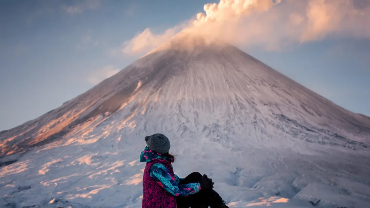 a tourist watches the eruption of the klyuchevskaya sopka volcano
