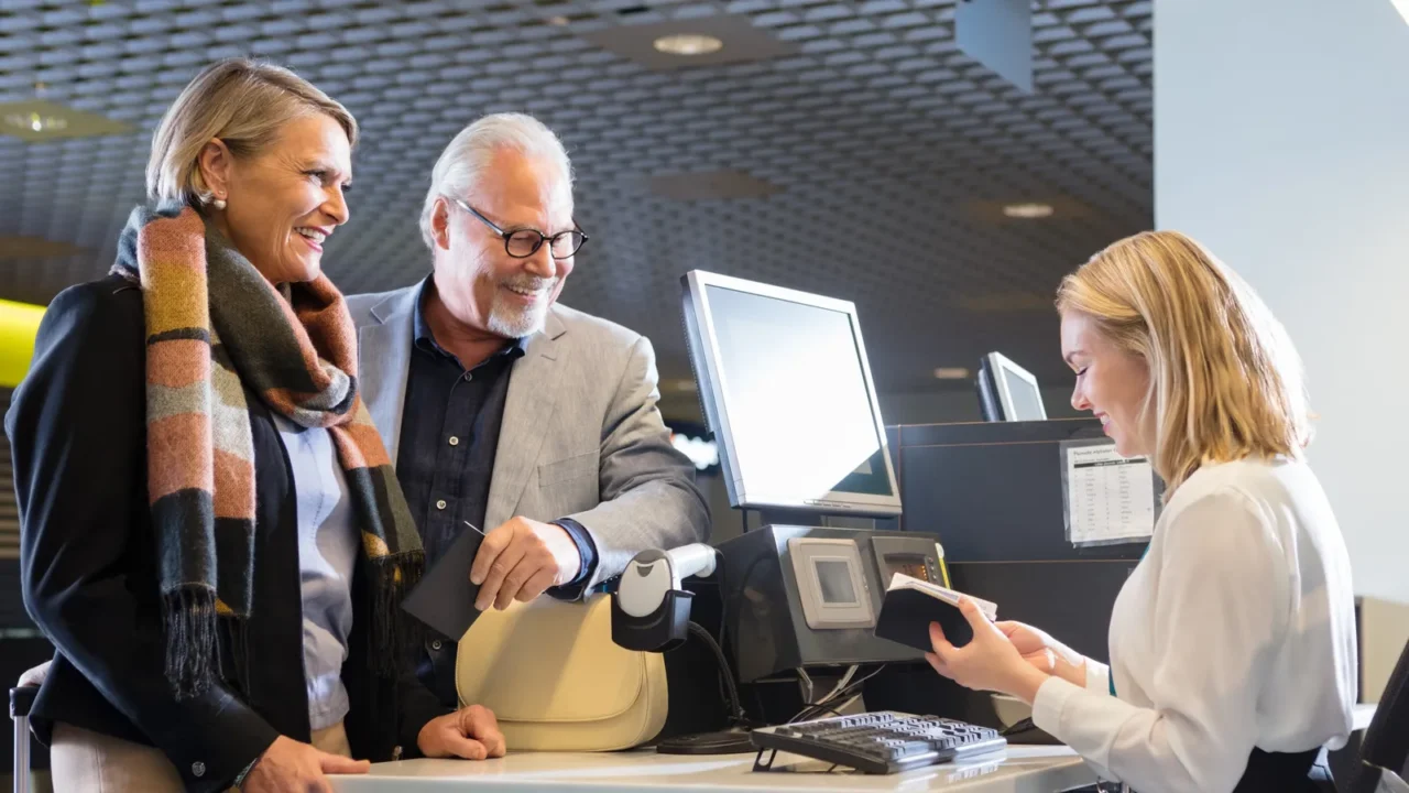 business couple looking at staff checking passport at airport ch