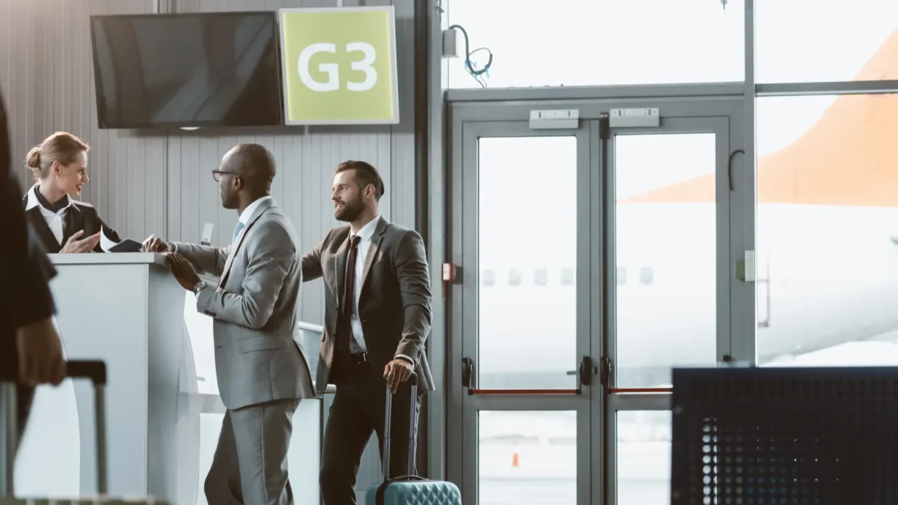 businessmen standing at airport reception to buy tickets while colleague