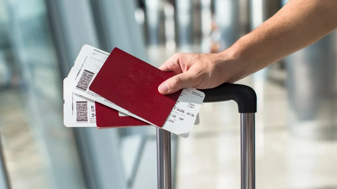 closeup of man holding passports and boarding pass at airport