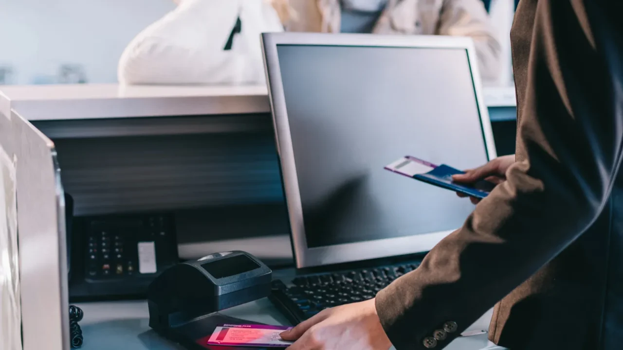 cropped shot of airport worker checking documents at checkin desk