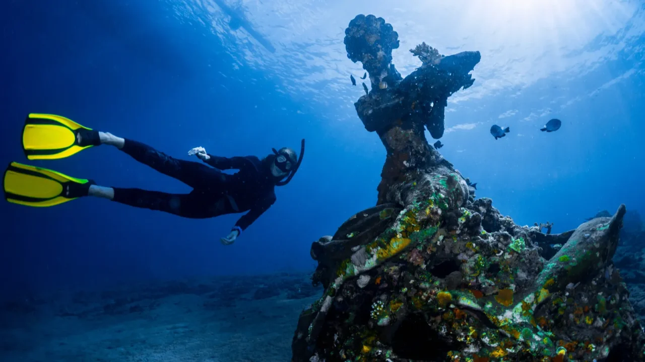 free diver exploring the underwater statue in a tropical sea