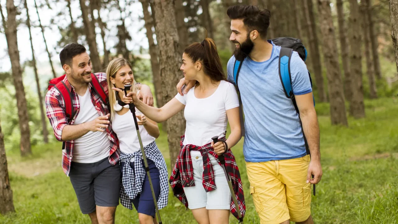 group of four friends hiking together through a forest at